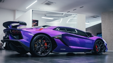 A purple Lamborghini Aventador SVJ hypercar is parked in showroom